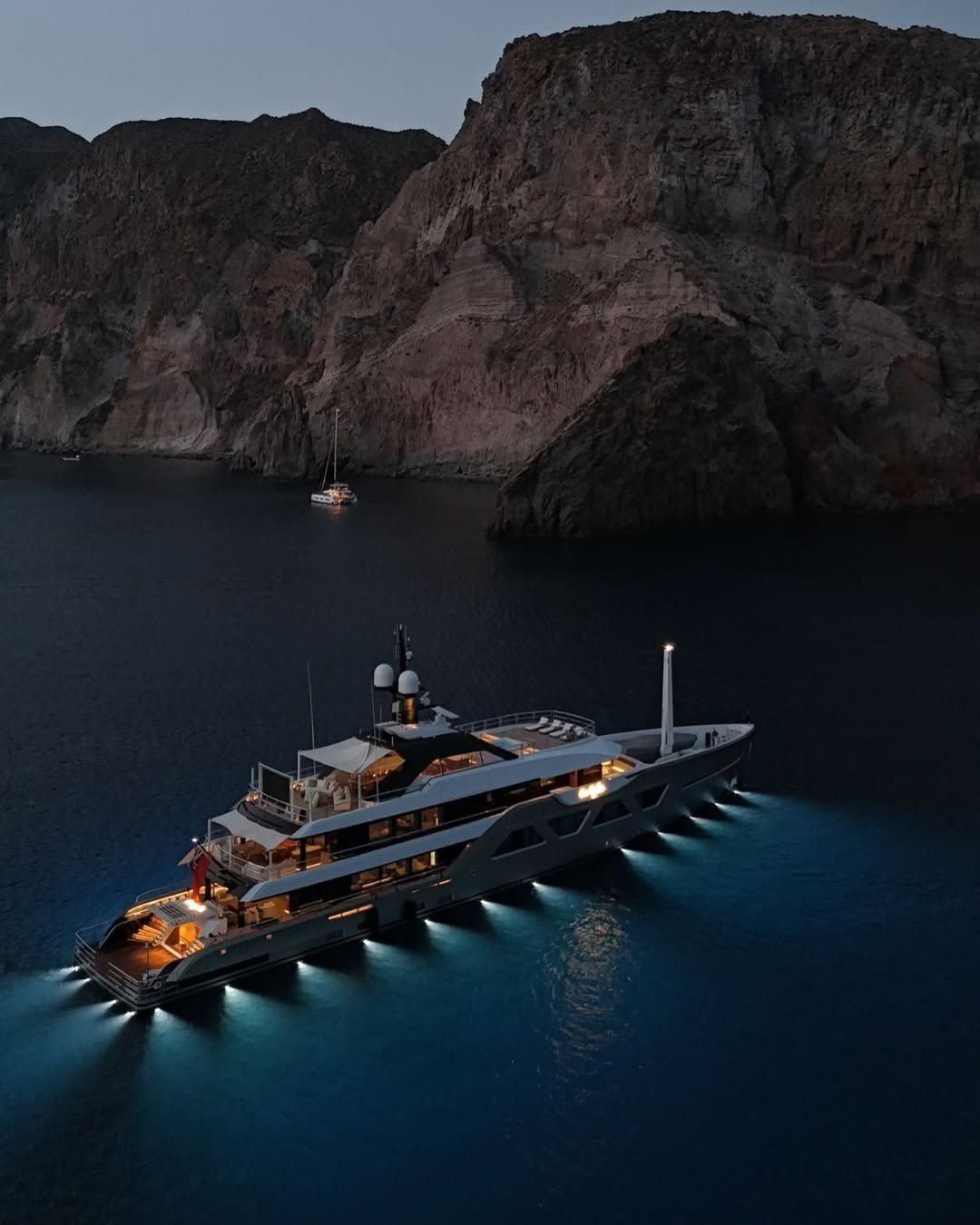 Yacht illuminato di notte in una baia riparata, con le luci subacquee accese